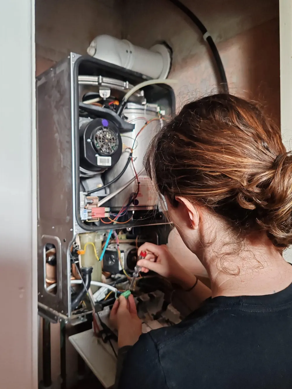 Rachel servicing a gas boiler with the front cover off