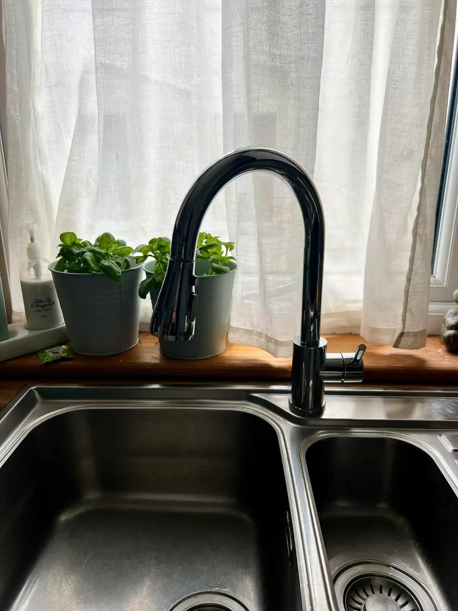 Black pull-out kitchen tap over a stainless steel sink